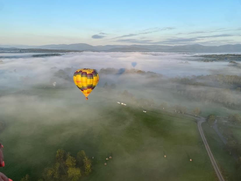 Hot air balloon drifting through morning fog over Virginia fields