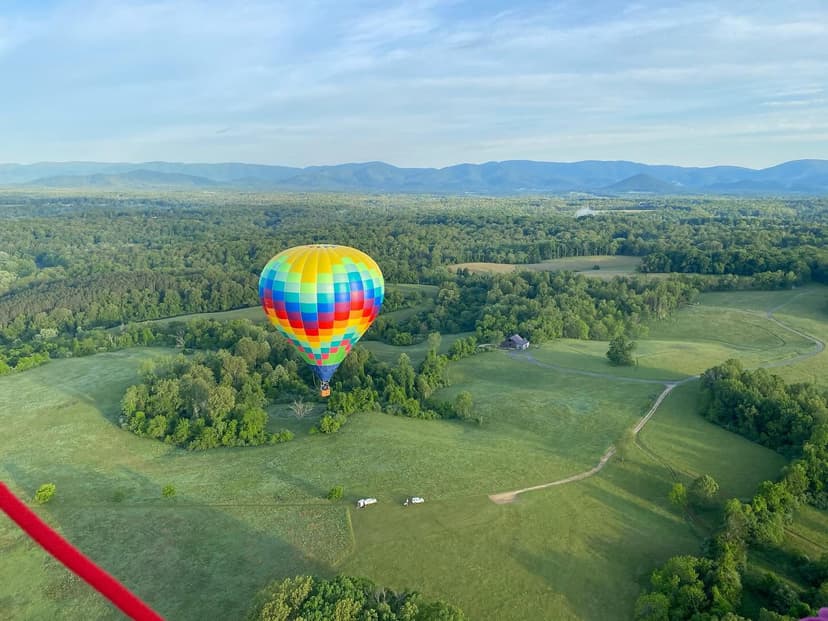 Hot air balloon over lush green Virginia countryside with Blue Ridge in distance