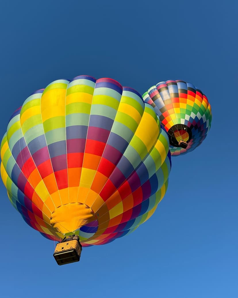 Two colorful hot air balloons flying together against blue sky